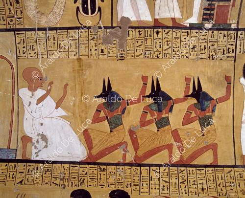 Inherkau inginocchiato di fronte a sacerdoti con la testa del dio Anubi.