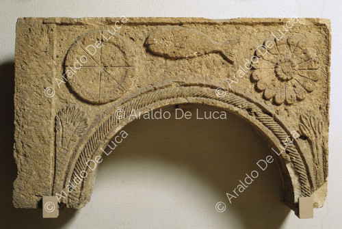 Stone arch decorated in relief with palmette flower and fish