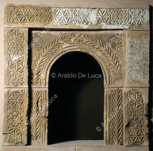 Arco de ventana de piedra decorado con palmetas y motivos geométricos