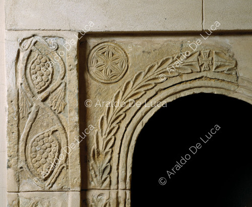 Arco di finestra in pietra decorato con palmette e motivi geometrici. Particolare