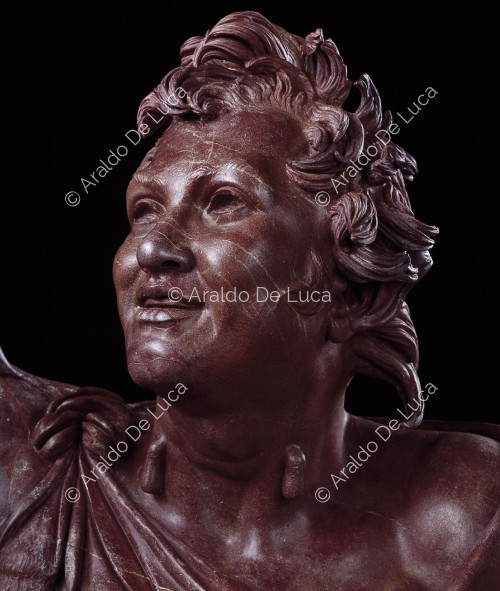 Statue of drunken Faun in antique red. Detail of the face
