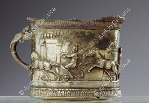 Coppa in argento decorata a sbalzo con auriga alato e manico antropomorfo