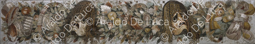 Emblema con festone con maschere, fiori, foglie e frutta. Mosaico